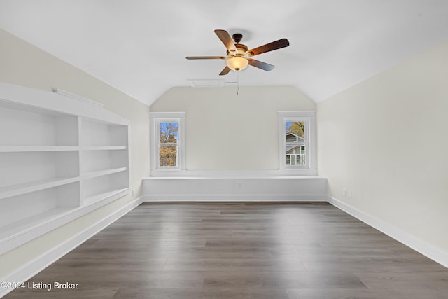 empty room featuring lofted ceiling, built in features, ceiling fan, and dark wood-type flooring