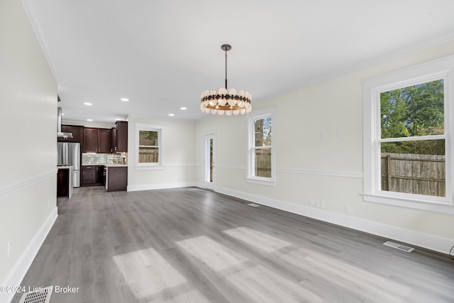 unfurnished living room with a notable chandelier, wood-type flooring, and crown molding