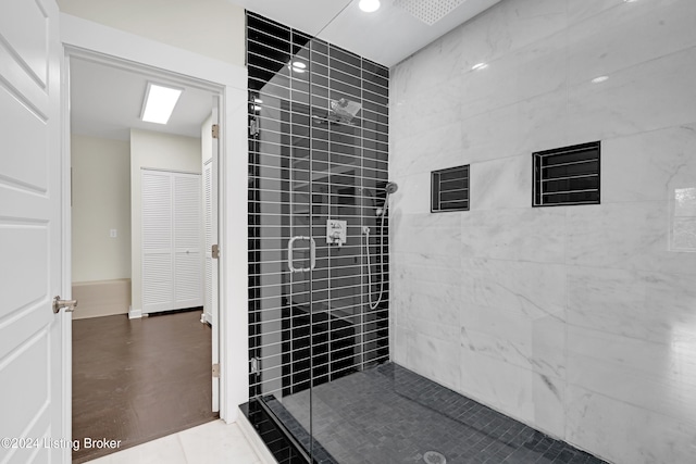 bathroom with concrete flooring and tiled shower