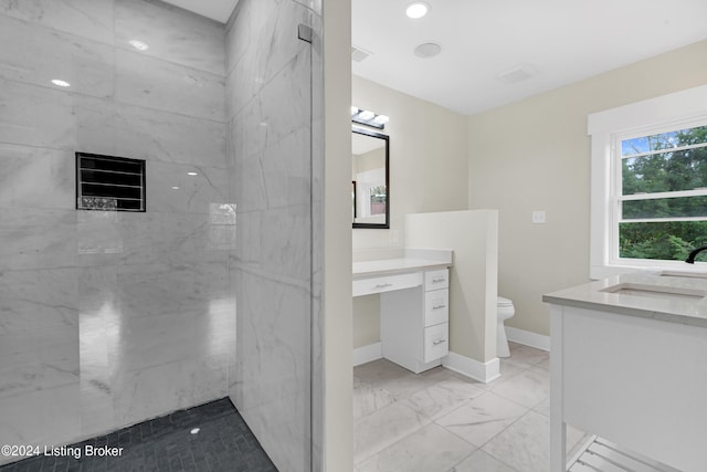 bathroom featuring tiled shower, vanity, and toilet