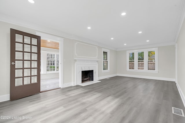 unfurnished living room featuring a premium fireplace, crown molding, and light hardwood / wood-style flooring