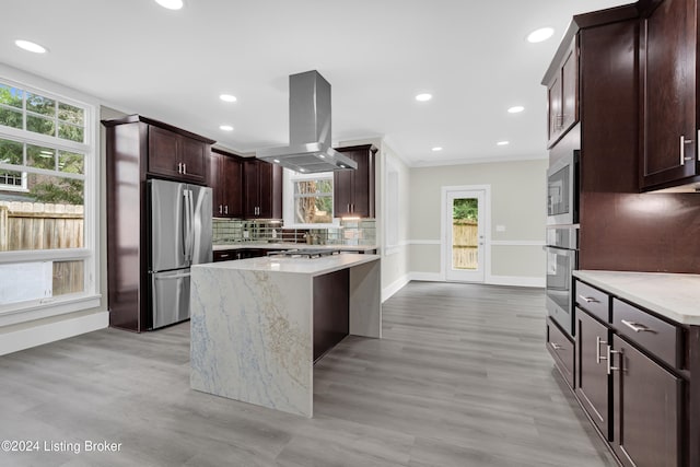 kitchen featuring a healthy amount of sunlight, island exhaust hood, light wood-type flooring, and stainless steel appliances