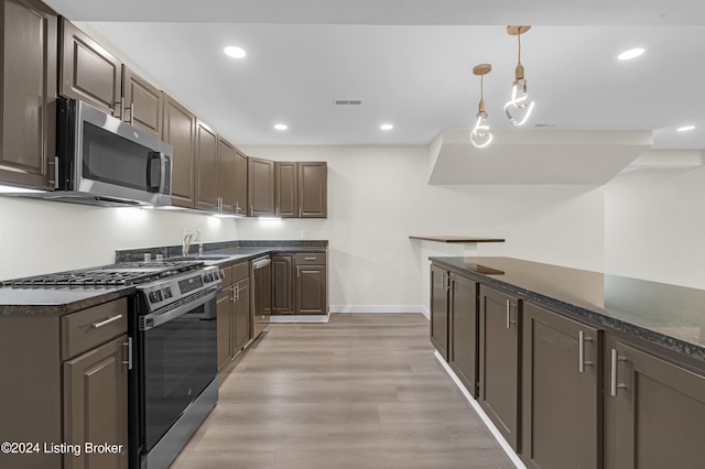 kitchen featuring sink, light wood-type flooring, black gas range oven, decorative light fixtures, and dark brown cabinetry