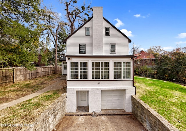 back of property featuring a garage and a lawn