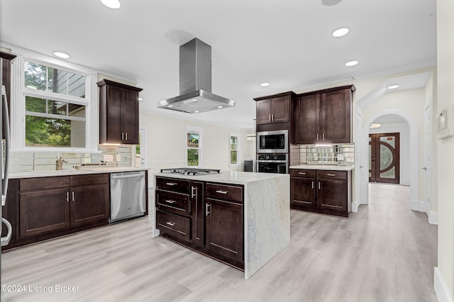 kitchen featuring appliances with stainless steel finishes, backsplash, light hardwood / wood-style flooring, and extractor fan