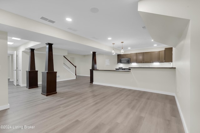 unfurnished living room featuring light hardwood / wood-style floors and ornate columns