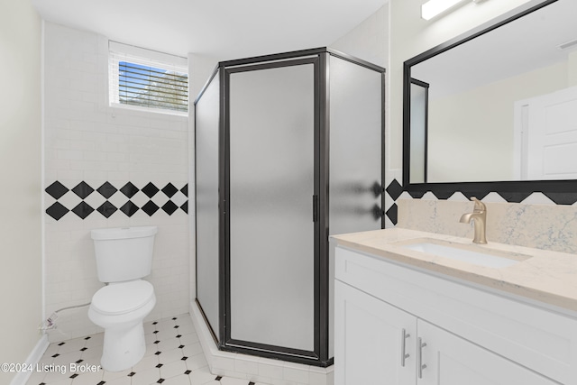 bathroom with tile patterned floors, vanity, a shower with shower door, and toilet