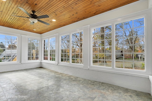 unfurnished sunroom featuring a wealth of natural light, ceiling fan, and wood ceiling