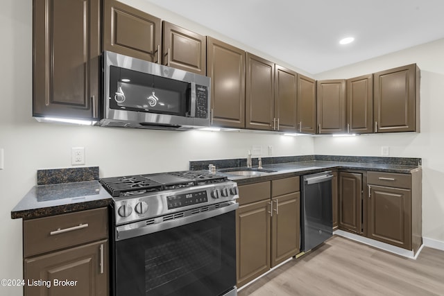 kitchen featuring dark brown cabinetry, sink, light hardwood / wood-style flooring, and appliances with stainless steel finishes