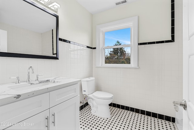 bathroom featuring vanity, toilet, and tile walls