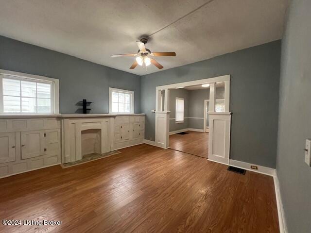 unfurnished living room with ceiling fan and dark wood-type flooring