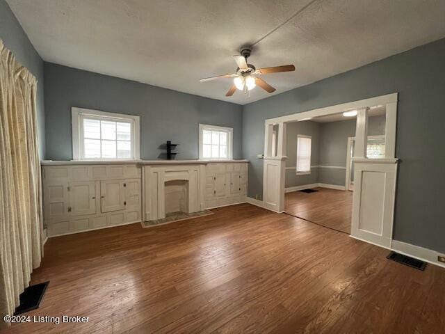 unfurnished bedroom featuring multiple windows, ceiling fan, and wood-type flooring