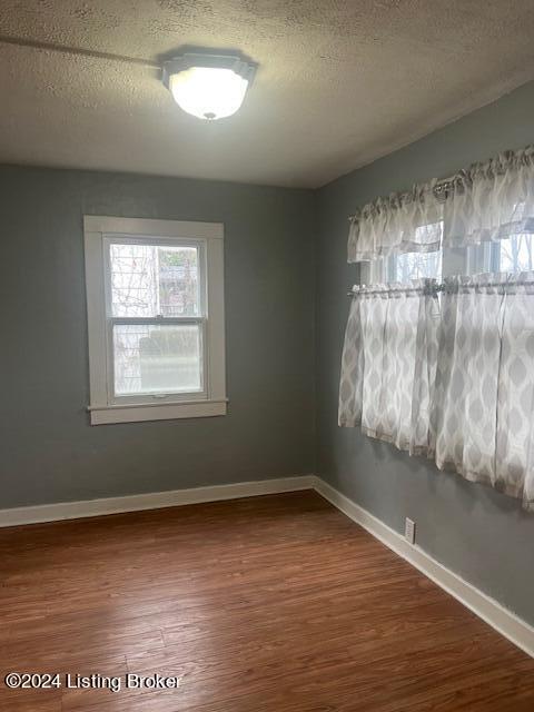 unfurnished room featuring hardwood / wood-style flooring and a textured ceiling