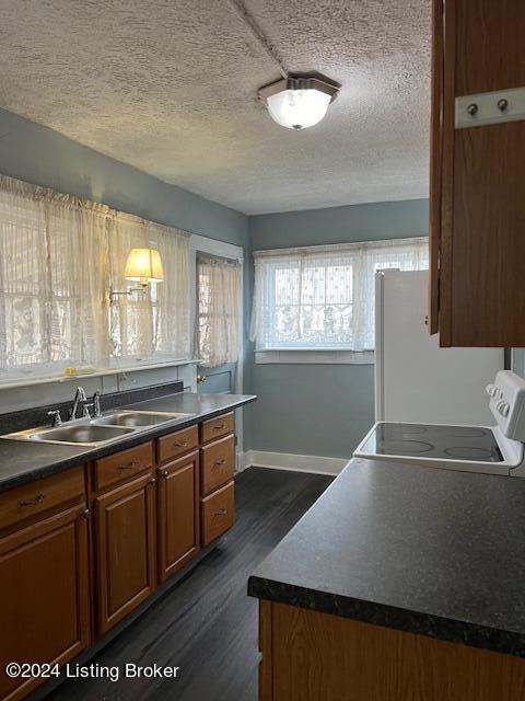 kitchen featuring a textured ceiling, sink, dark wood-type flooring, and white appliances