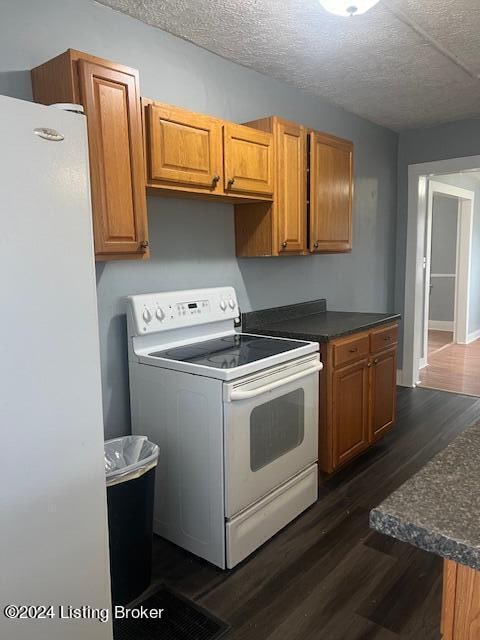 kitchen featuring dark hardwood / wood-style flooring, white appliances, and a textured ceiling