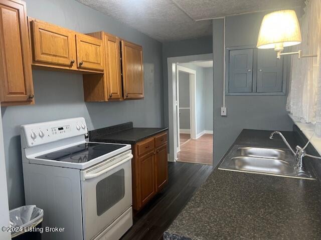 kitchen with a textured ceiling, dark hardwood / wood-style floors, white range with electric stovetop, and sink