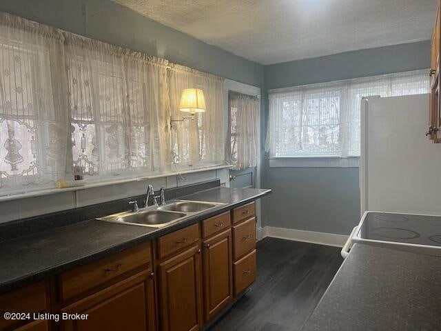 kitchen with stove, sink, a textured ceiling, white fridge, and dark hardwood / wood-style flooring