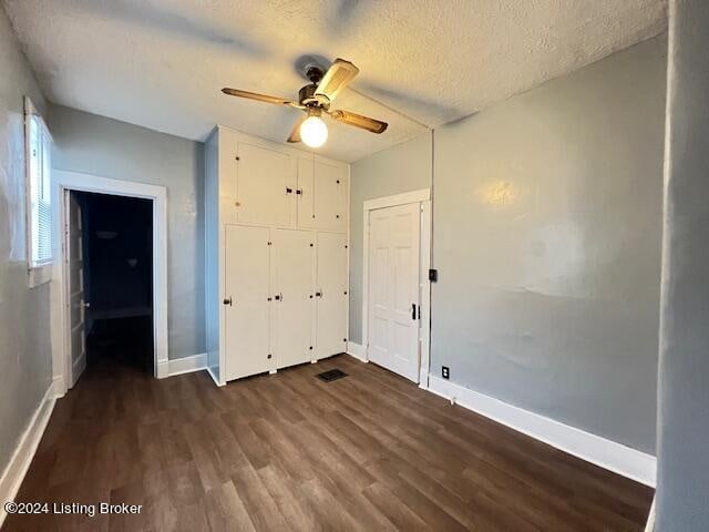 unfurnished bedroom featuring ceiling fan, dark hardwood / wood-style flooring, and a textured ceiling