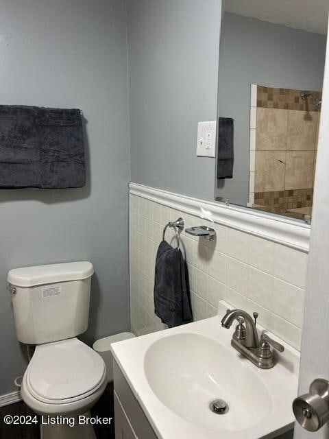 bathroom with vanity, toilet, and tile walls