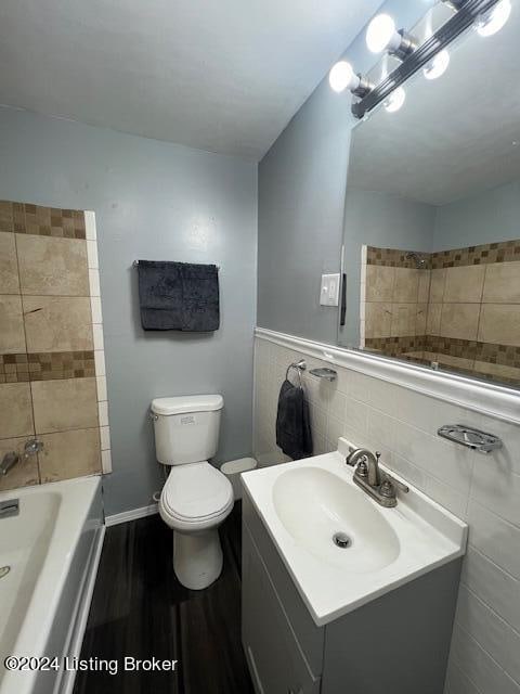 bathroom featuring toilet, vanity, tile walls, and hardwood / wood-style flooring