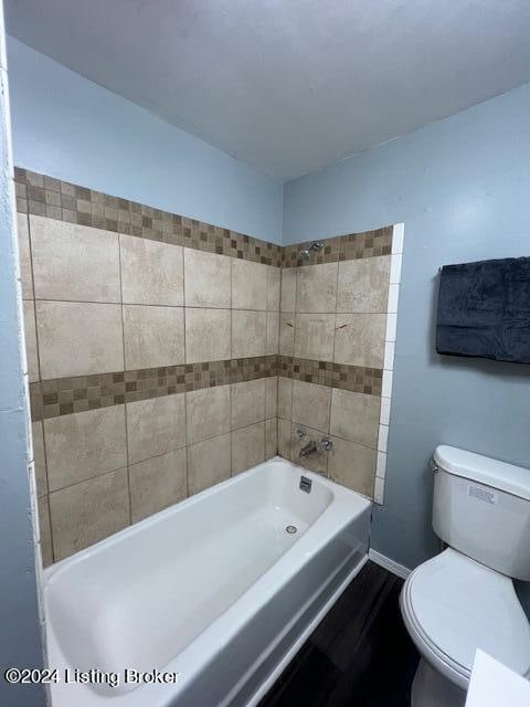 bathroom with tiled shower / bath combo and toilet