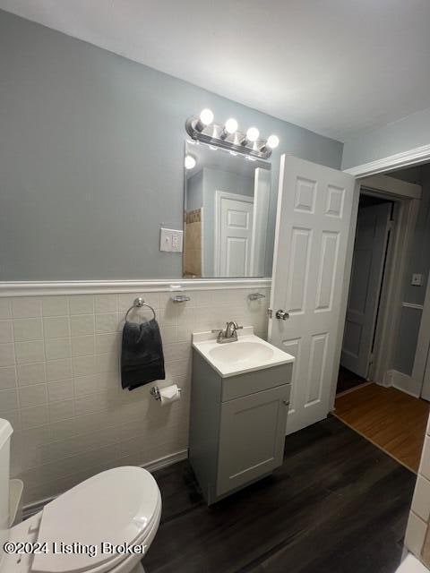 bathroom featuring hardwood / wood-style floors, vanity, tile walls, and toilet