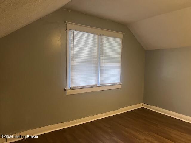 bonus room featuring plenty of natural light, dark hardwood / wood-style flooring, and vaulted ceiling