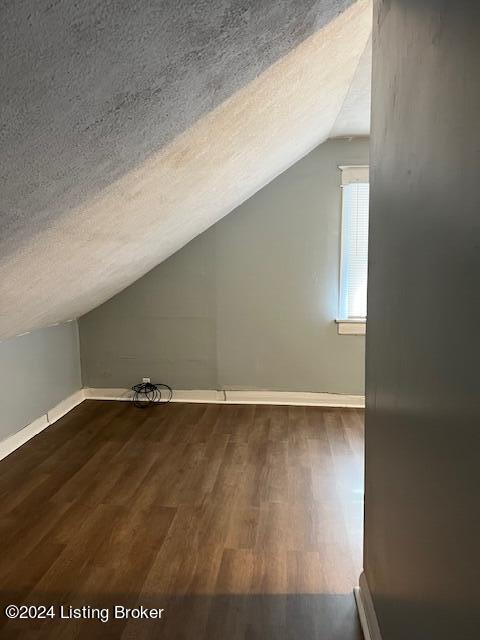 bonus room with a textured ceiling, dark wood-type flooring, and lofted ceiling