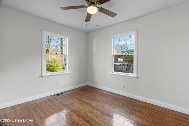 empty room with a wealth of natural light, ceiling fan, and wood-type flooring