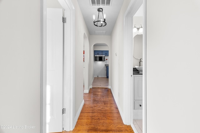 hallway with wood-type flooring and an inviting chandelier