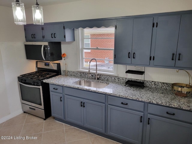 kitchen with decorative light fixtures, gas stove, light tile patterned flooring, and sink