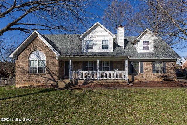 new england style home featuring a porch and a front lawn