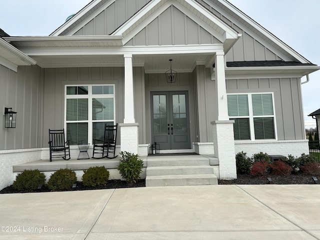 view of exterior entry featuring french doors and a porch