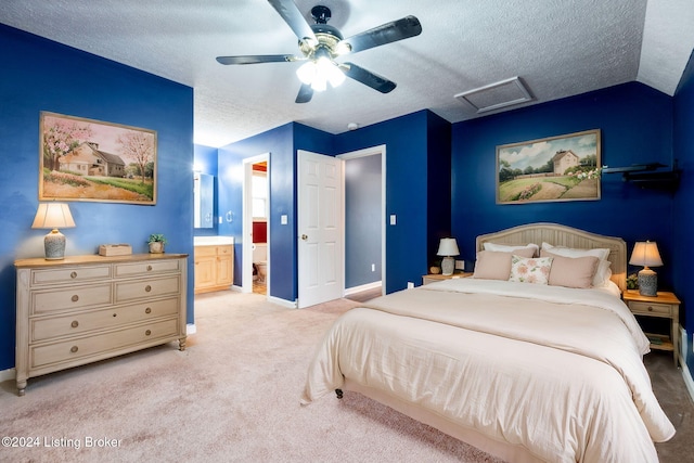 carpeted bedroom featuring a textured ceiling, ensuite bathroom, vaulted ceiling, and ceiling fan