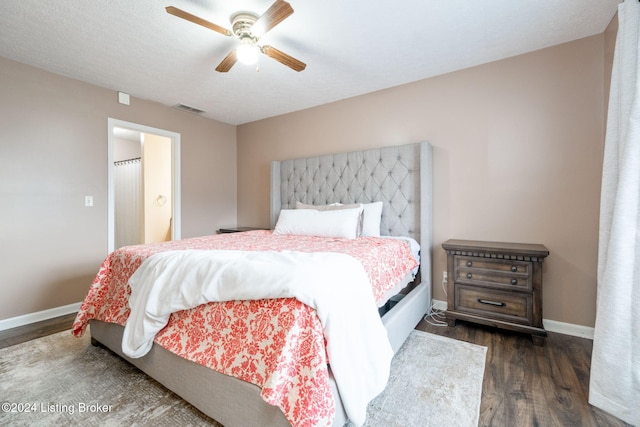 bedroom with a textured ceiling, ceiling fan, and dark wood-type flooring