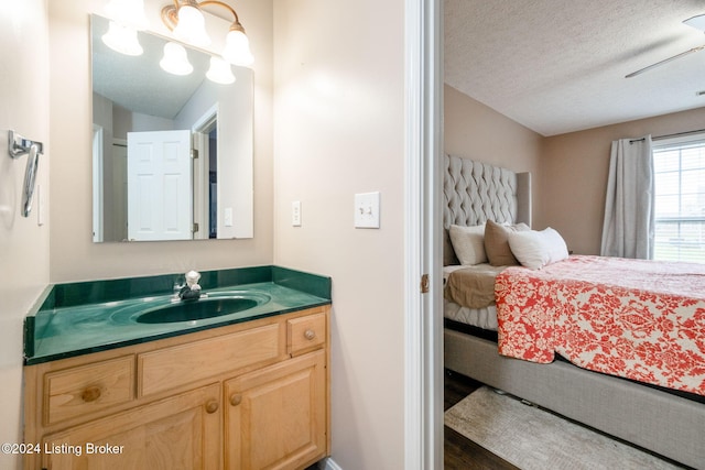 bathroom with vanity, a textured ceiling, ceiling fan, wood-type flooring, and lofted ceiling