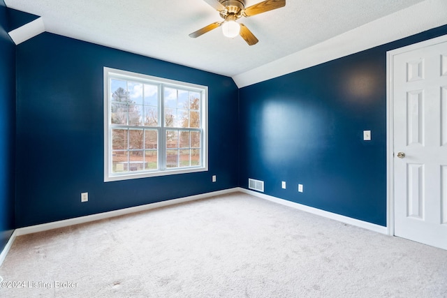 carpeted empty room with a textured ceiling, ceiling fan, and lofted ceiling