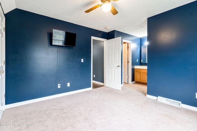 unfurnished bedroom with ensuite bath, ceiling fan, light carpet, and lofted ceiling