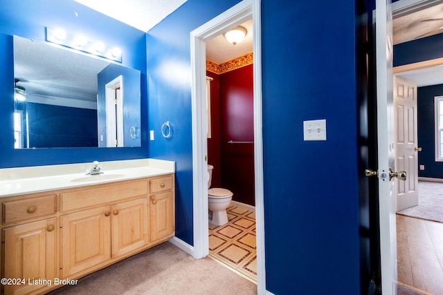 bathroom featuring ceiling fan, toilet, a textured ceiling, and vanity