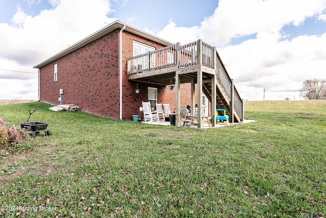 rear view of property with a lawn, a patio area, and a wooden deck