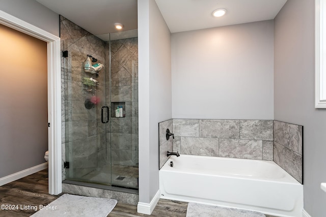 bathroom with hardwood / wood-style flooring, separate shower and tub, and toilet