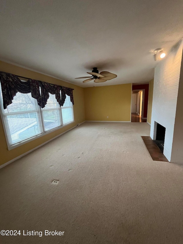 unfurnished living room featuring a fireplace, carpet, and ceiling fan