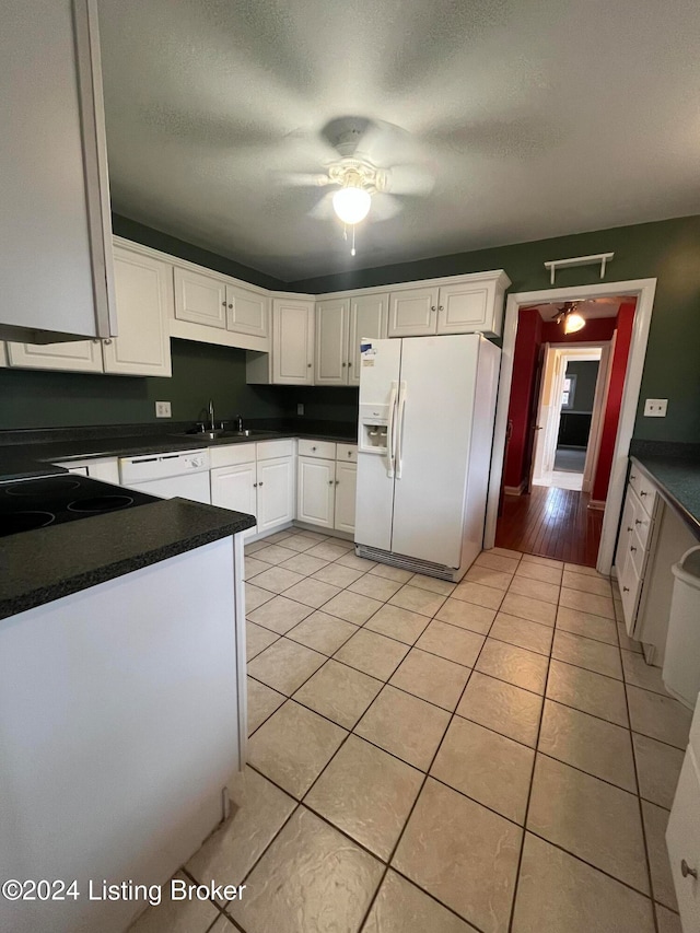 kitchen featuring white cabinets, white appliances, a textured ceiling, and light tile patterned floors