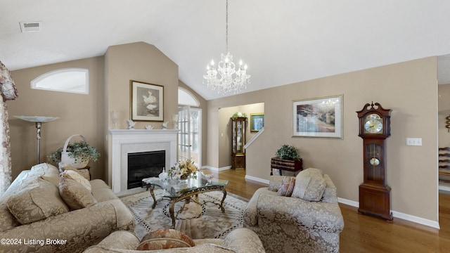 living room with a fireplace, an inviting chandelier, high vaulted ceiling, and hardwood / wood-style flooring