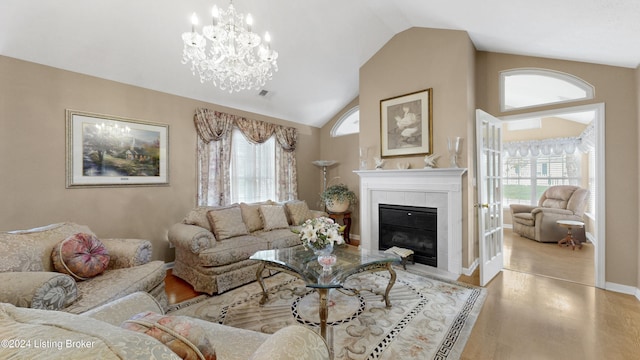 living room featuring a notable chandelier, a fireplace, vaulted ceiling, and light wood-type flooring