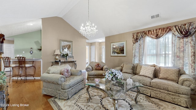 living room with light hardwood / wood-style floors, lofted ceiling, and an inviting chandelier