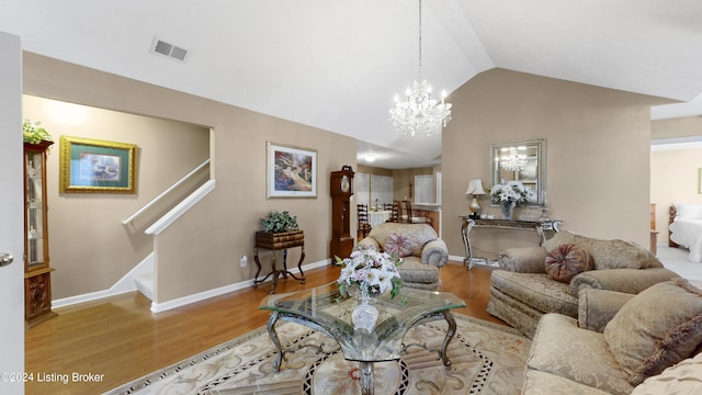 living room with a notable chandelier, lofted ceiling, and light wood-type flooring