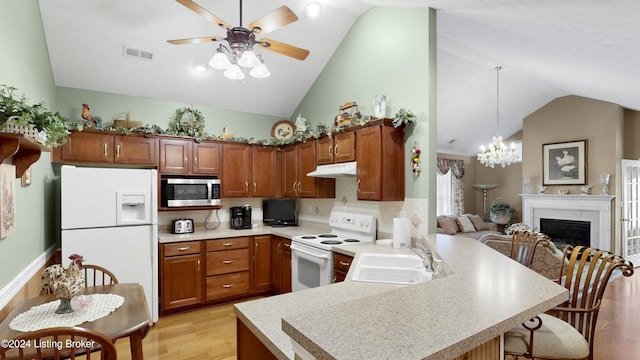 kitchen with white appliances, vaulted ceiling, sink, pendant lighting, and light hardwood / wood-style floors