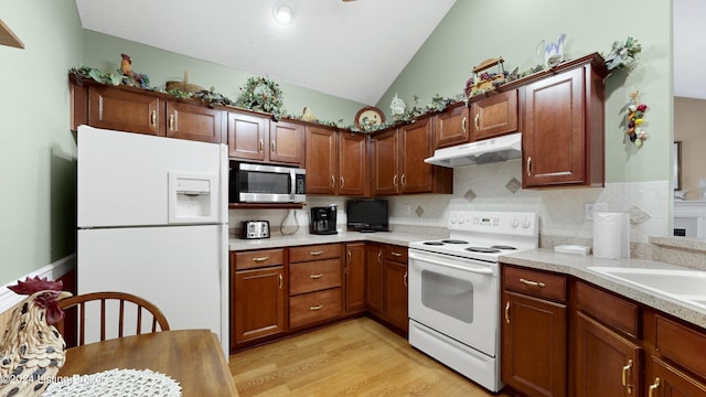 kitchen featuring decorative backsplash, white appliances, light hardwood / wood-style floors, and vaulted ceiling