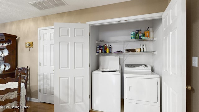 laundry area with wood-type flooring, a textured ceiling, and washer and clothes dryer